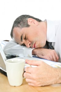 Businessman asleep at his desk on white background